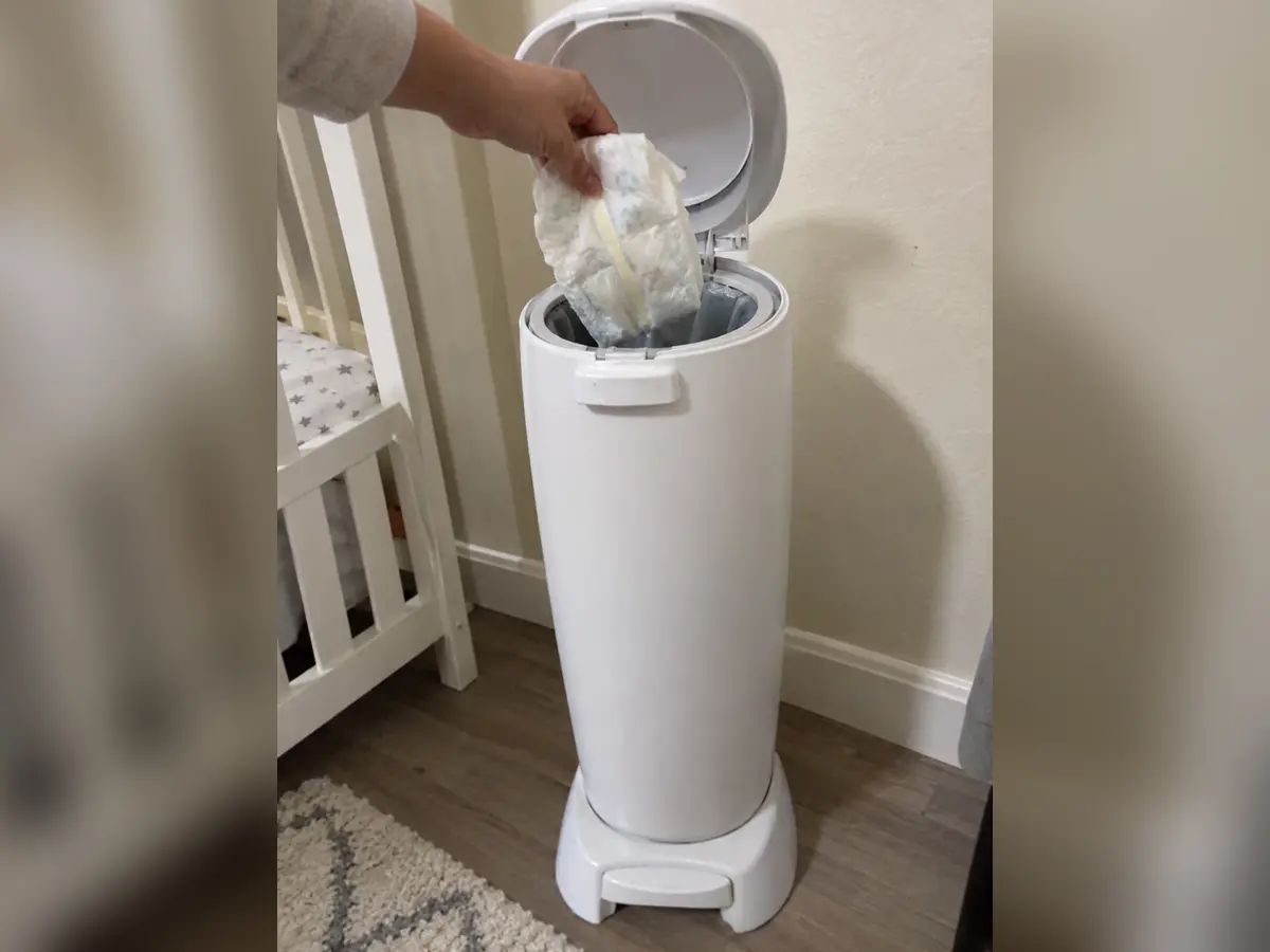 Dropping a diaper into our Diaper Genie Complete beside the cot, before we moved it out of the nursery, original photo
