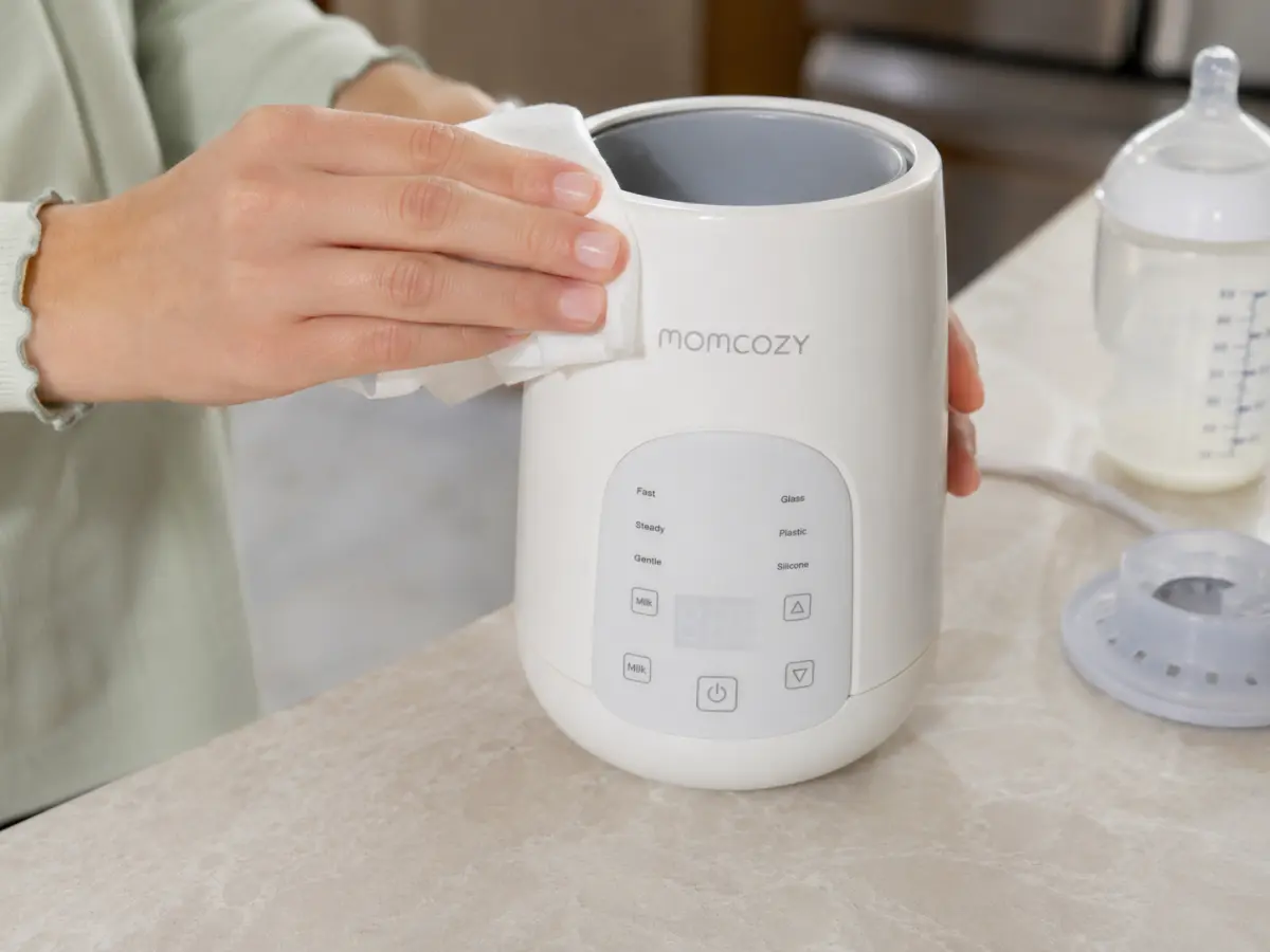 Wiping out the chamber of a countertop bottle warmer with a soapy cloth after use